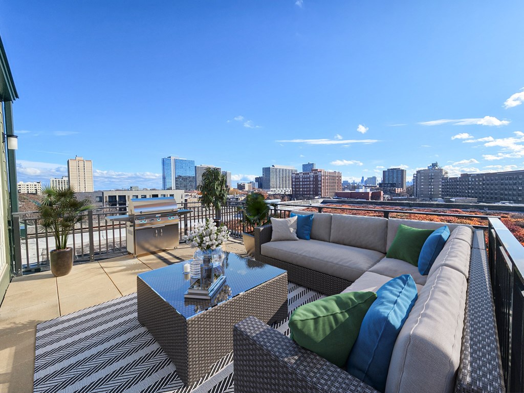 a rooftop deck with couches and a table overlooking the city