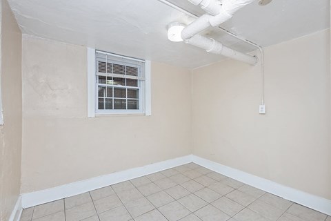 A room with a window and a white pipe on the ceiling.