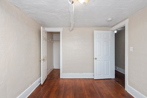 A room with a white door and a wooden floor.