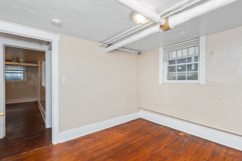 A room with a wooden floor and a window with blinds.