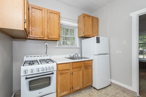 A kitchen with a white stove and wooden cabinets.