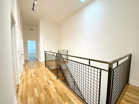 A long hallway with wood floors and black metal railings.