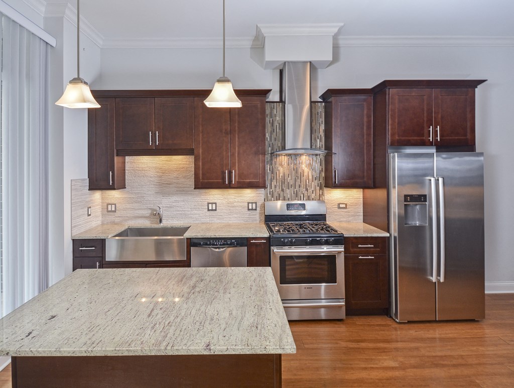 a large kitchen with stainless steel appliances and marble counter tops