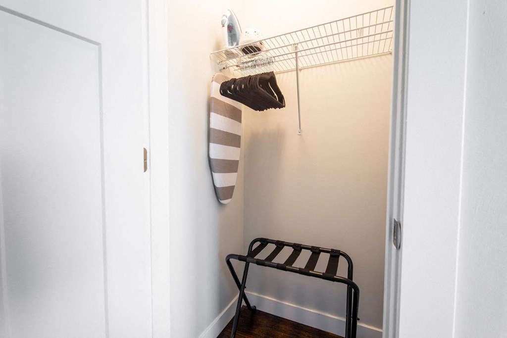 a white closet with a black and white striped towel and a shoe rack