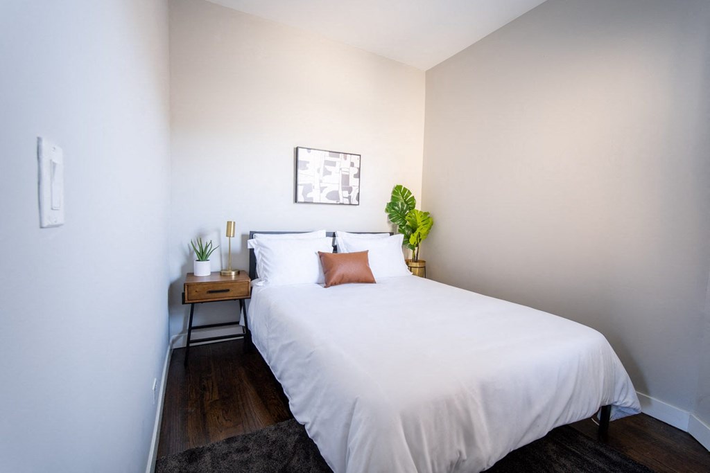 a bedroom with a white bed and a wooden floor