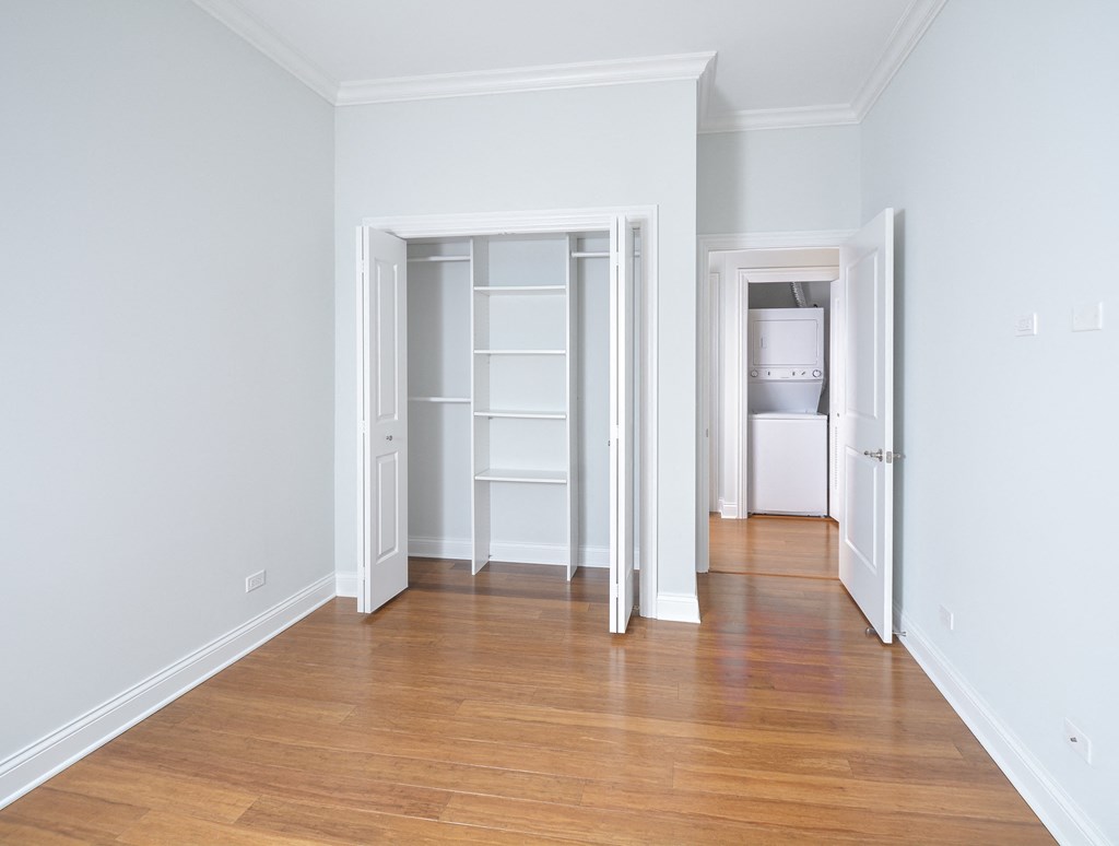 an empty living room with a hard wood floor and an open closet