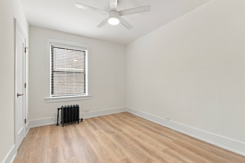 A room with a fan, window, and radiator.