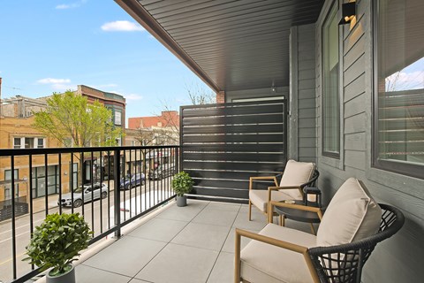 A balcony with two chairs and a table.