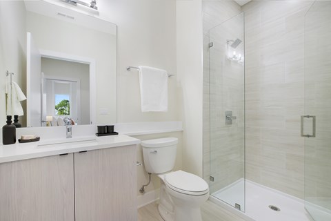 A white bathroom with a toilet, sink, and shower.