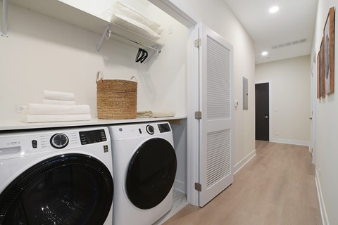 A laundry room with two washing machines and a basket of towels.