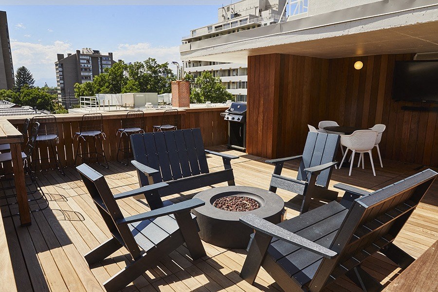 a rooftop deck with chairs and a fire pit