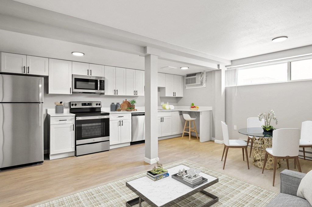 a kitchen and living room with white cabinets and stainless steel appliances