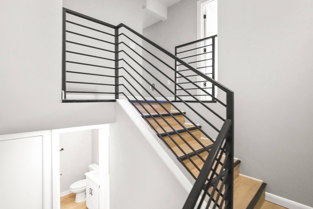 a stairwell in a home with black metal railings and a white toilet