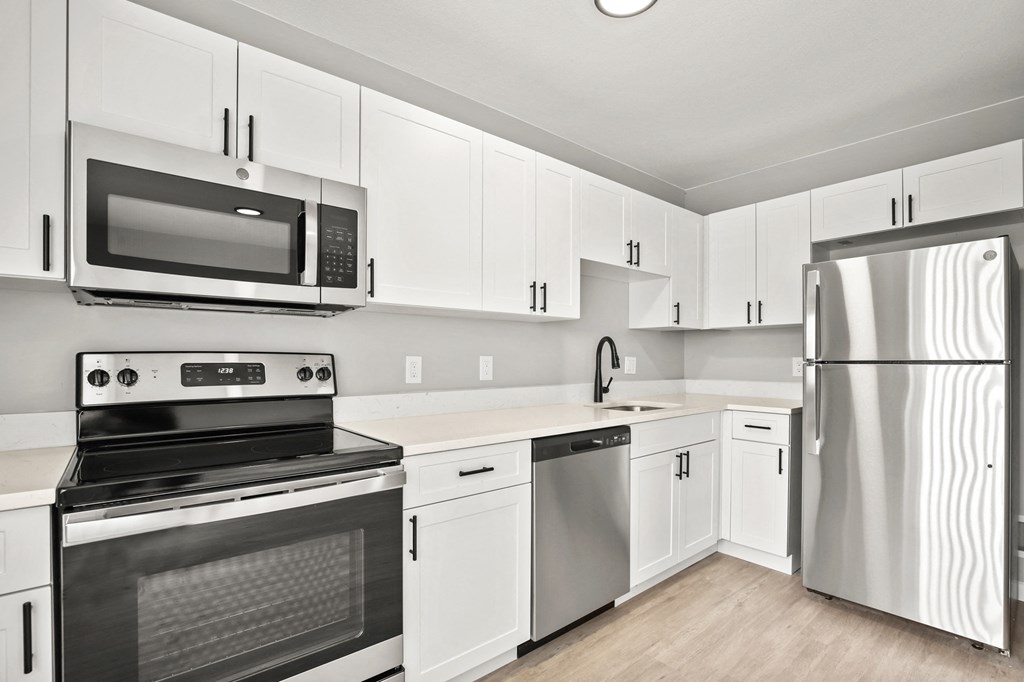 an empty kitchen with white cabinets and stainless steel appliances