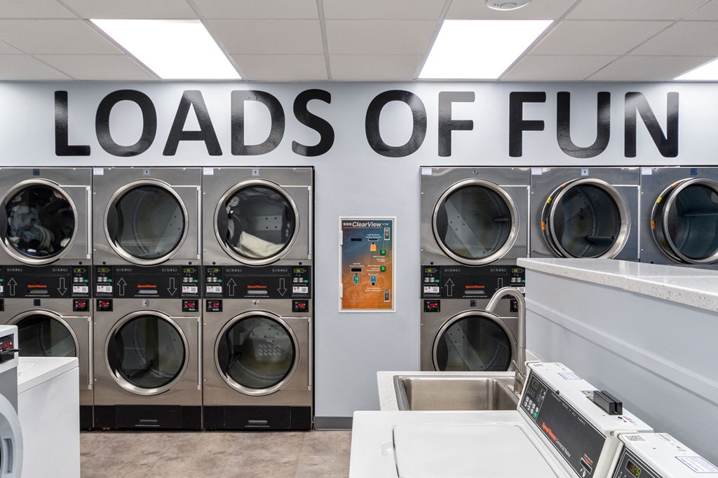 a laundry room with a row of washers and dryers and a wall with