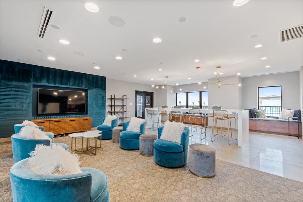 a living room with blue chairs and a bar and a television