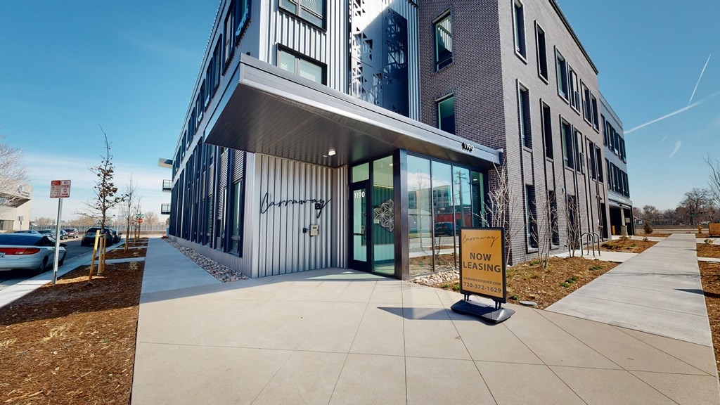 A modern building with a glass entrance and a sign that says "NOW LEASING".