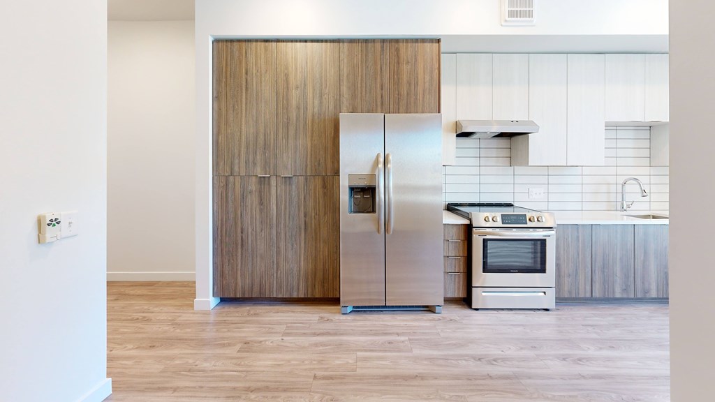 A kitchen with a refrigerator, oven, and microwave.