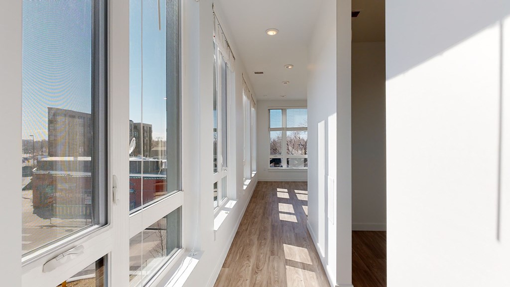 A long hallway with white walls and wood floors.