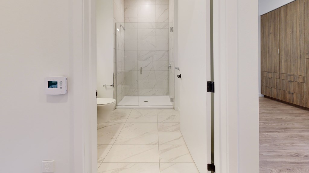 A bathroom with a walk-in shower and a wooden door.