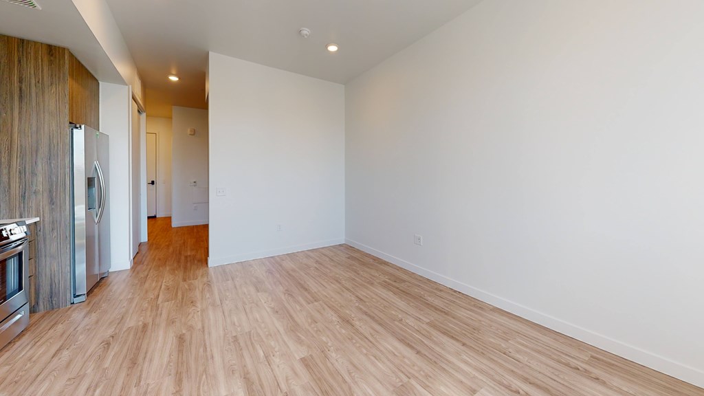 A spacious room with wooden flooring and white walls.