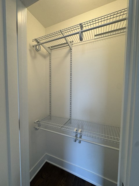 A white closet with a metal rod shelf.