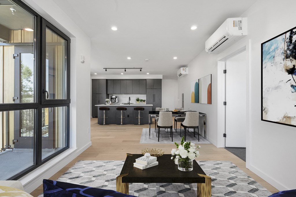 a living room with a couch and a coffee table and a kitchen in the background