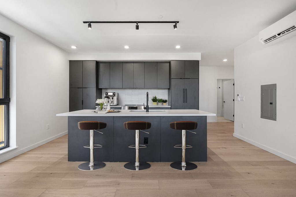 a kitchen with a large island with bar stools and dark cabinets