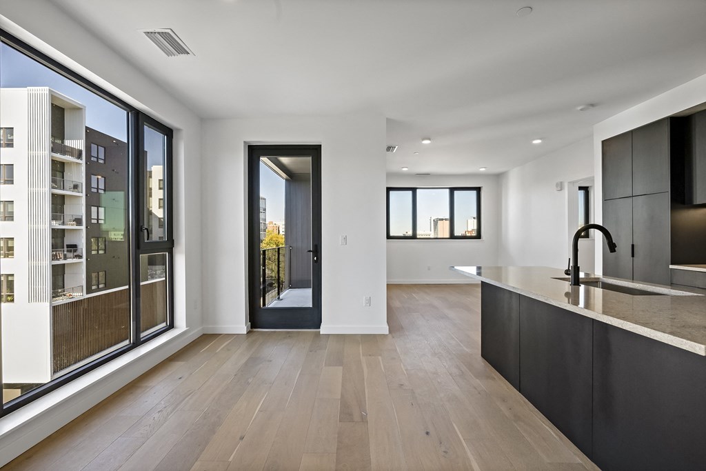 a large living room with a kitchen and a door to a balcony