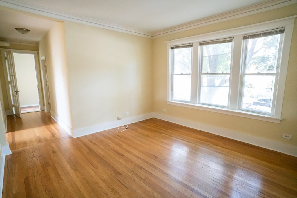 an empty living room with wooden floors and three windows