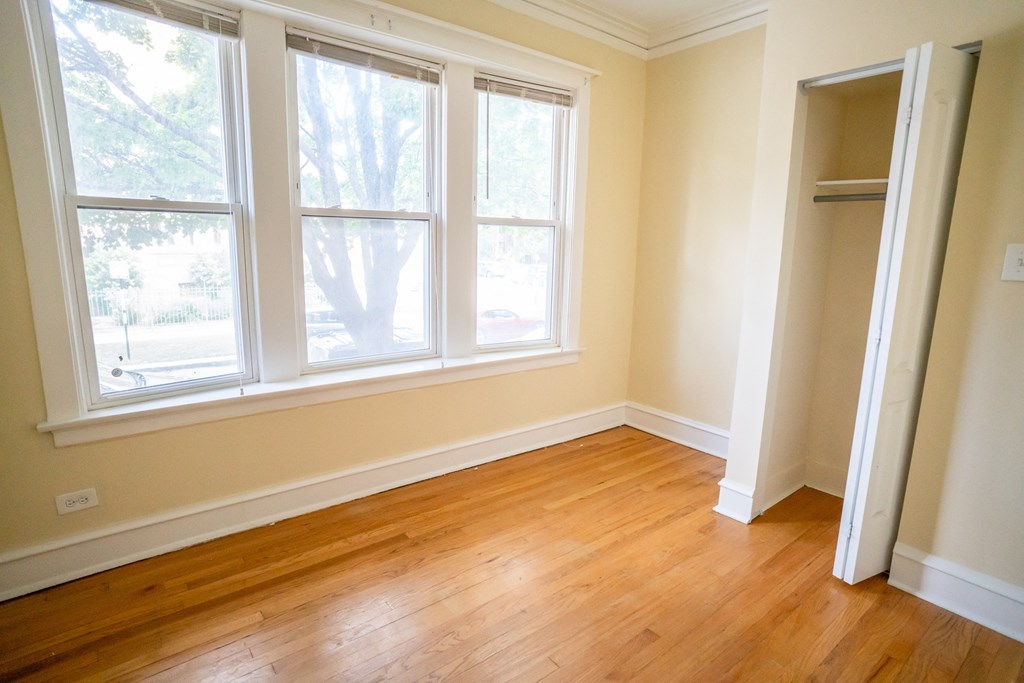an empty room with a wooden floor and three windows