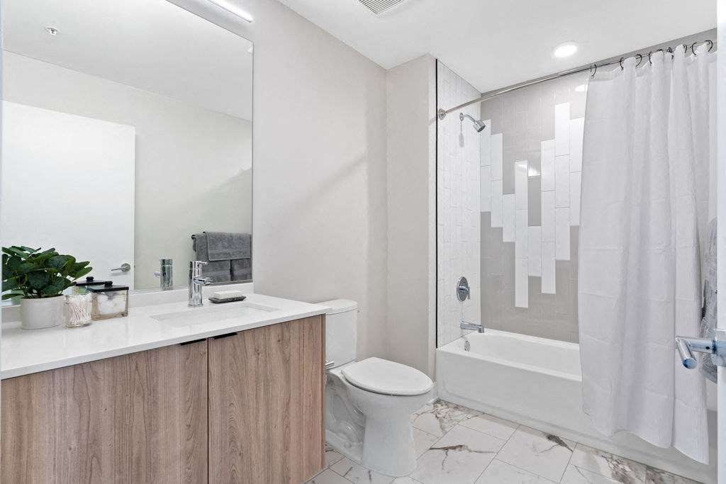 a bathroom with a designer shower tile with tub surround and a toilet and a sink featuring wide plank flooring