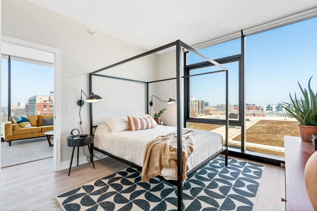 a bedroom with floor to ceiling windows a bed and tall ceilings