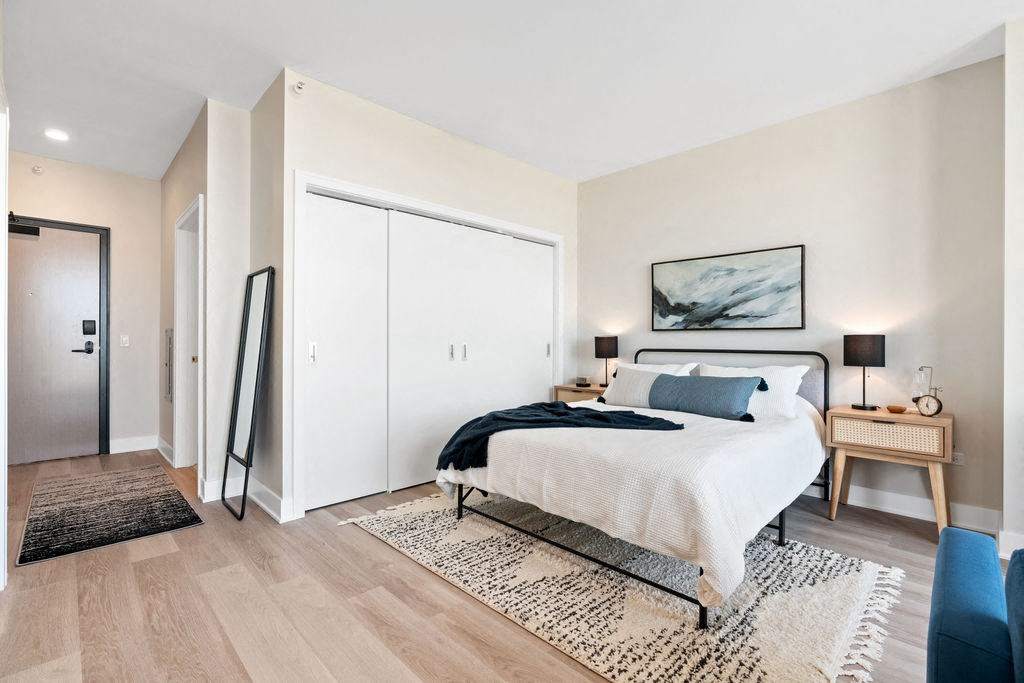 a bedroom with a bed and a closet and wide plank flooring