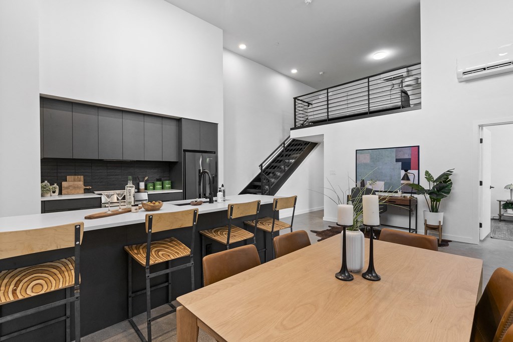 a dining room with a table and chairs and a kitchen with a staircase