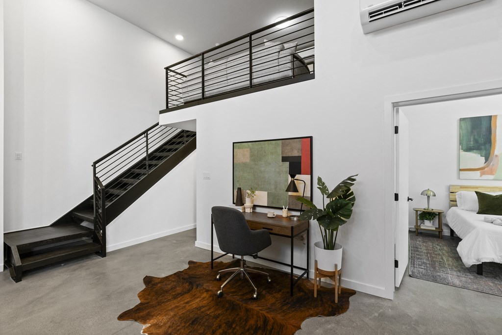 a living room with a desk and a staircase in a house