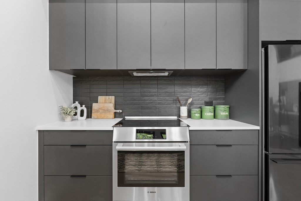 a kitchen with gray cabinets and a stove and a refrigerator