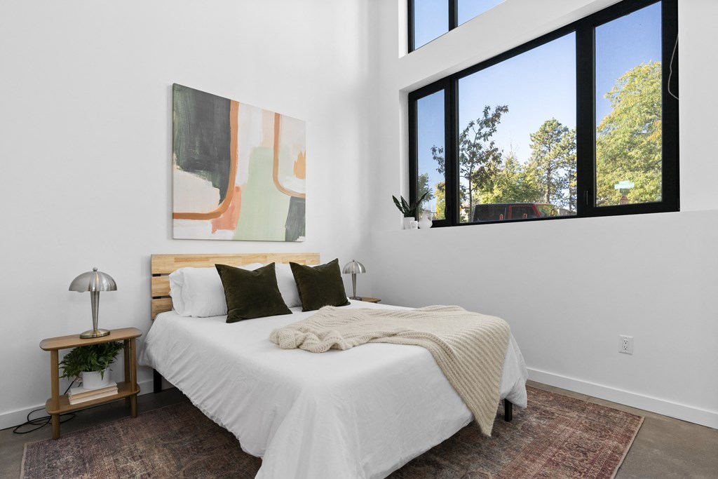 a bedroom with a large bed and large windows