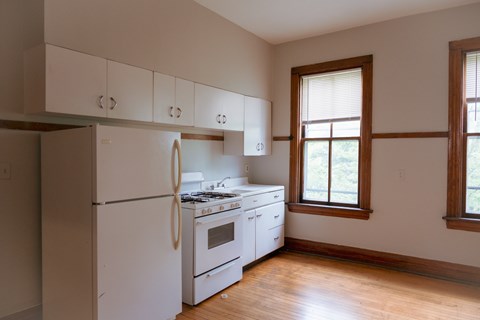 A white kitchen with a refrigerator, stove, and cabinets.