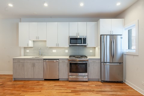 A modern kitchen with wooden floors and stainless steel appliances.