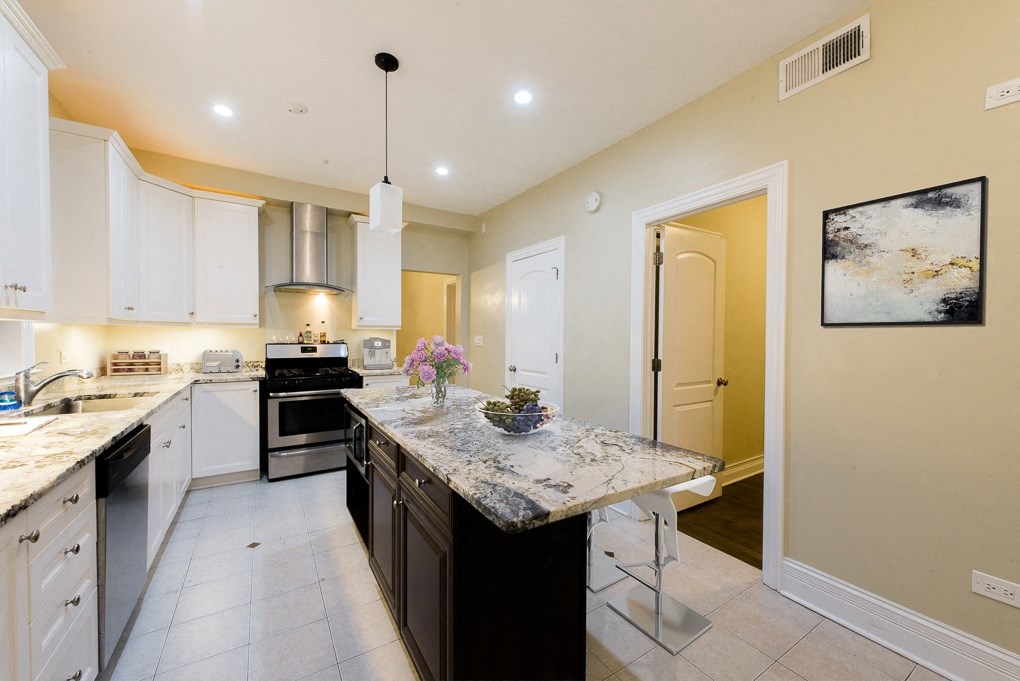 a kitchen with white cabinets and a marble counter top