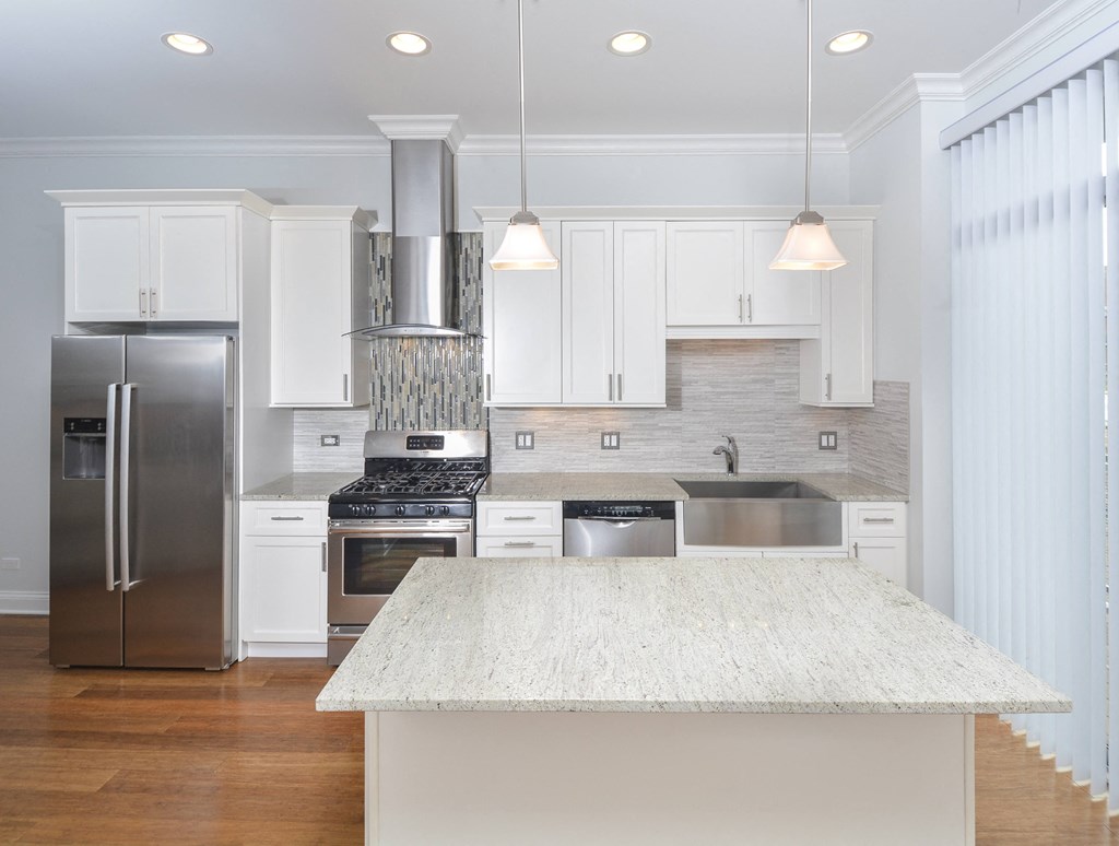 a large white kitchen with stainless steel appliances and a white island