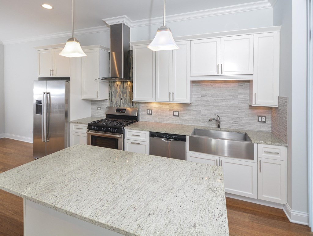 a white kitchen with stainless steel appliances and a white counter top