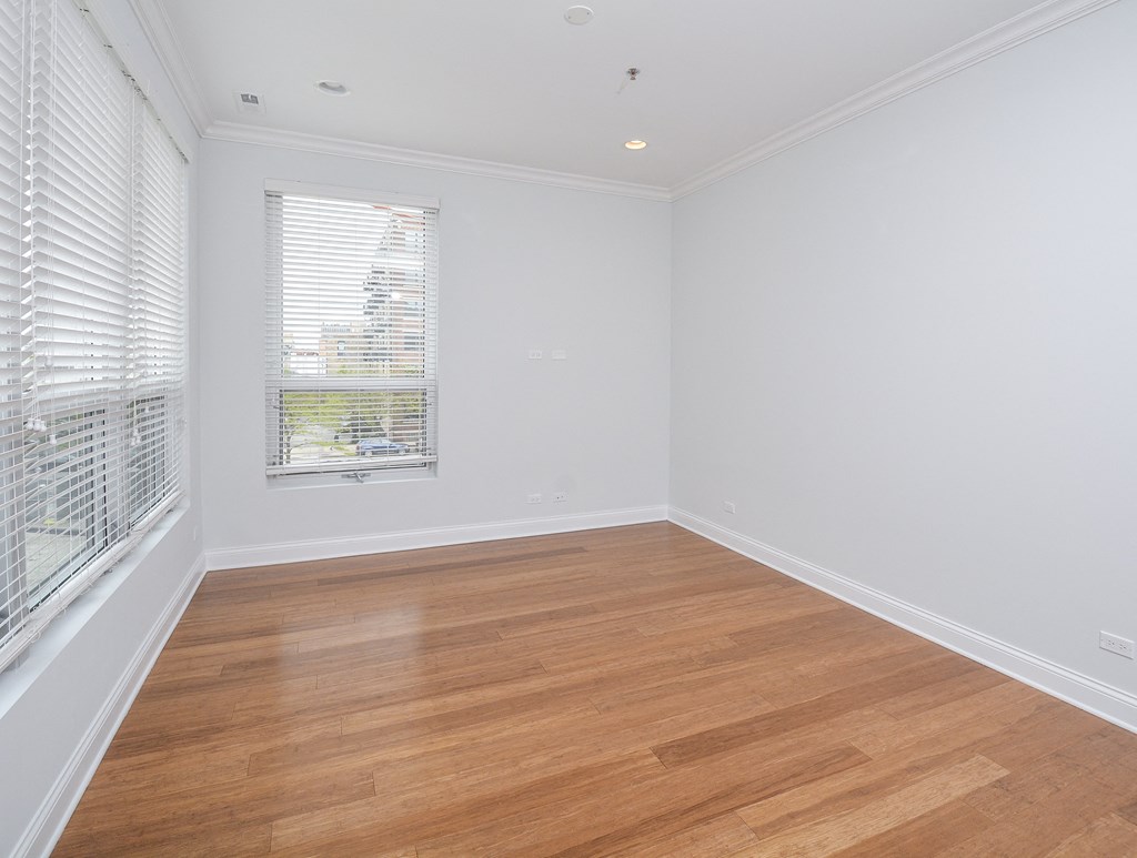 a living room with white walls and wood floors and a window