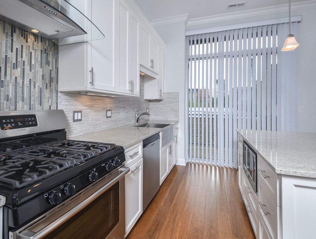 a kitchen with white cabinets and a stove and a window