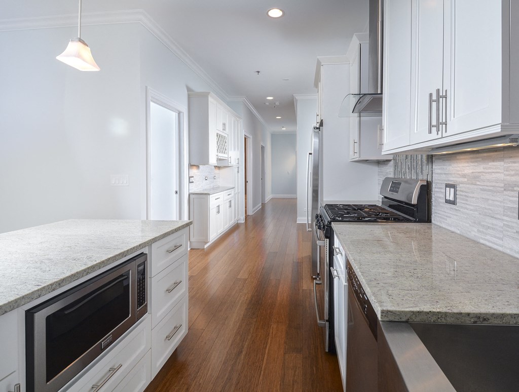 a large kitchen with marble counter tops and white cabinets