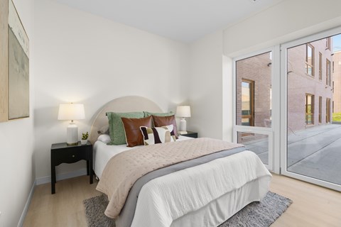 A bedroom with a large bed and a view of the street outside.