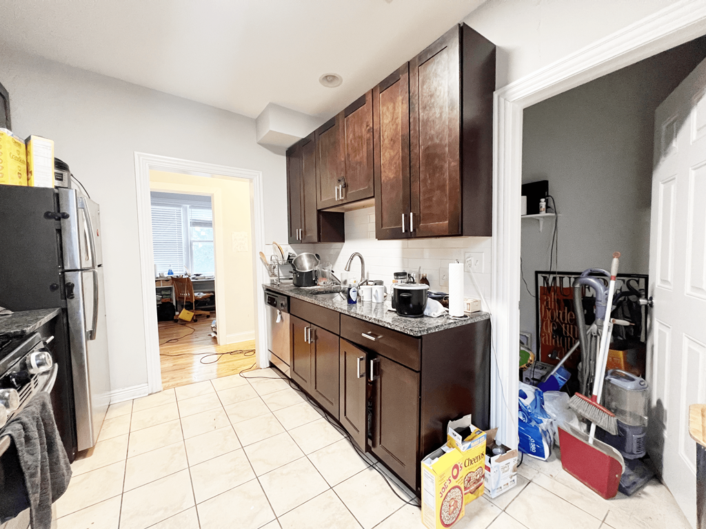 a kitchen with wooden cabinets and a white tiled floor
