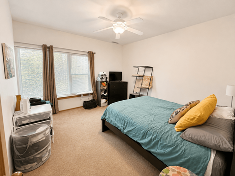A bedroom with a bed, dresser, and window.