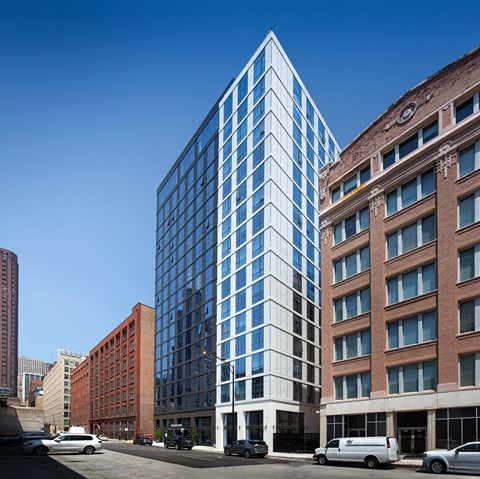 A modern glass building stands next to an older brick building.